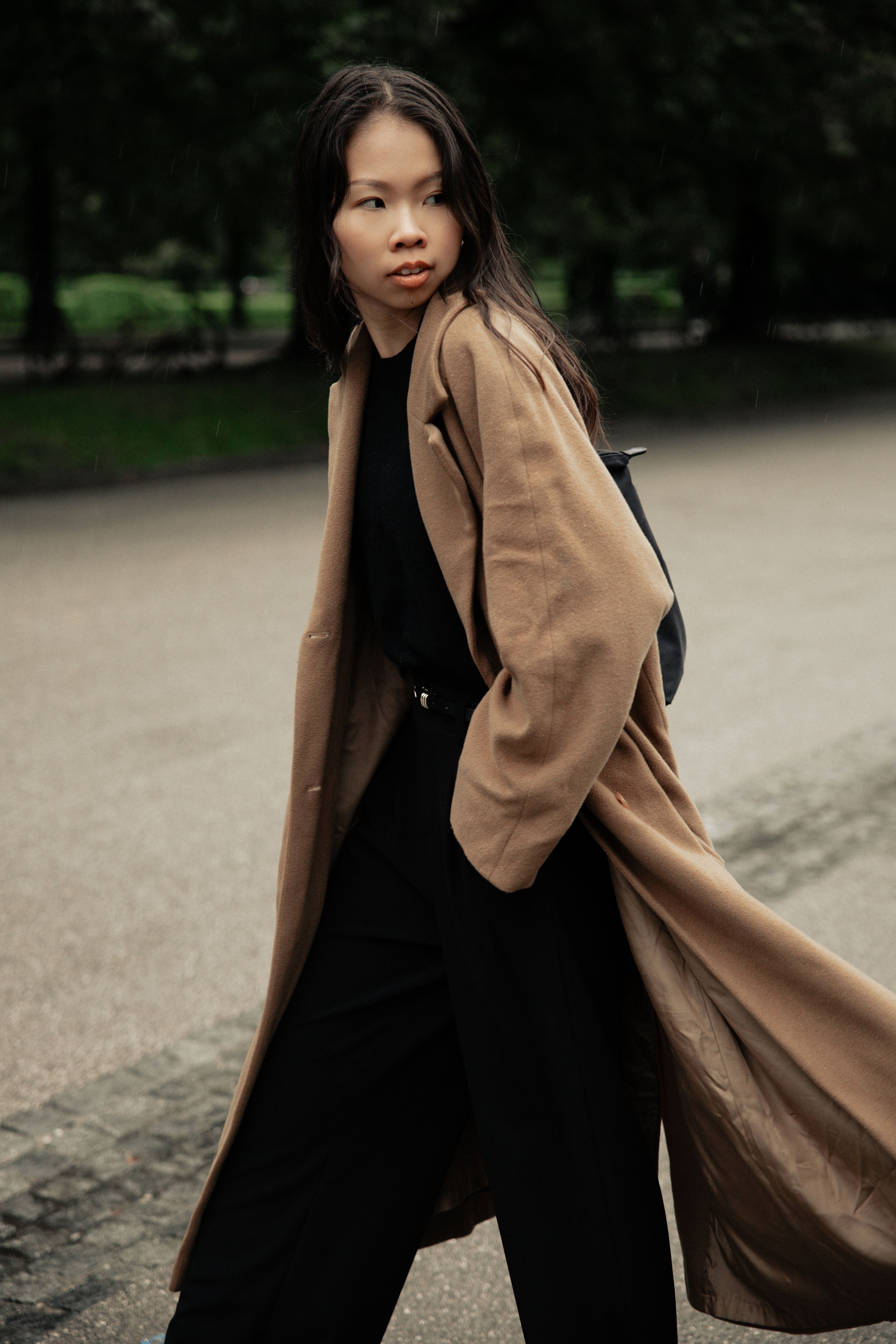 Elegant woman in long trench coat walking outside on a rainy day