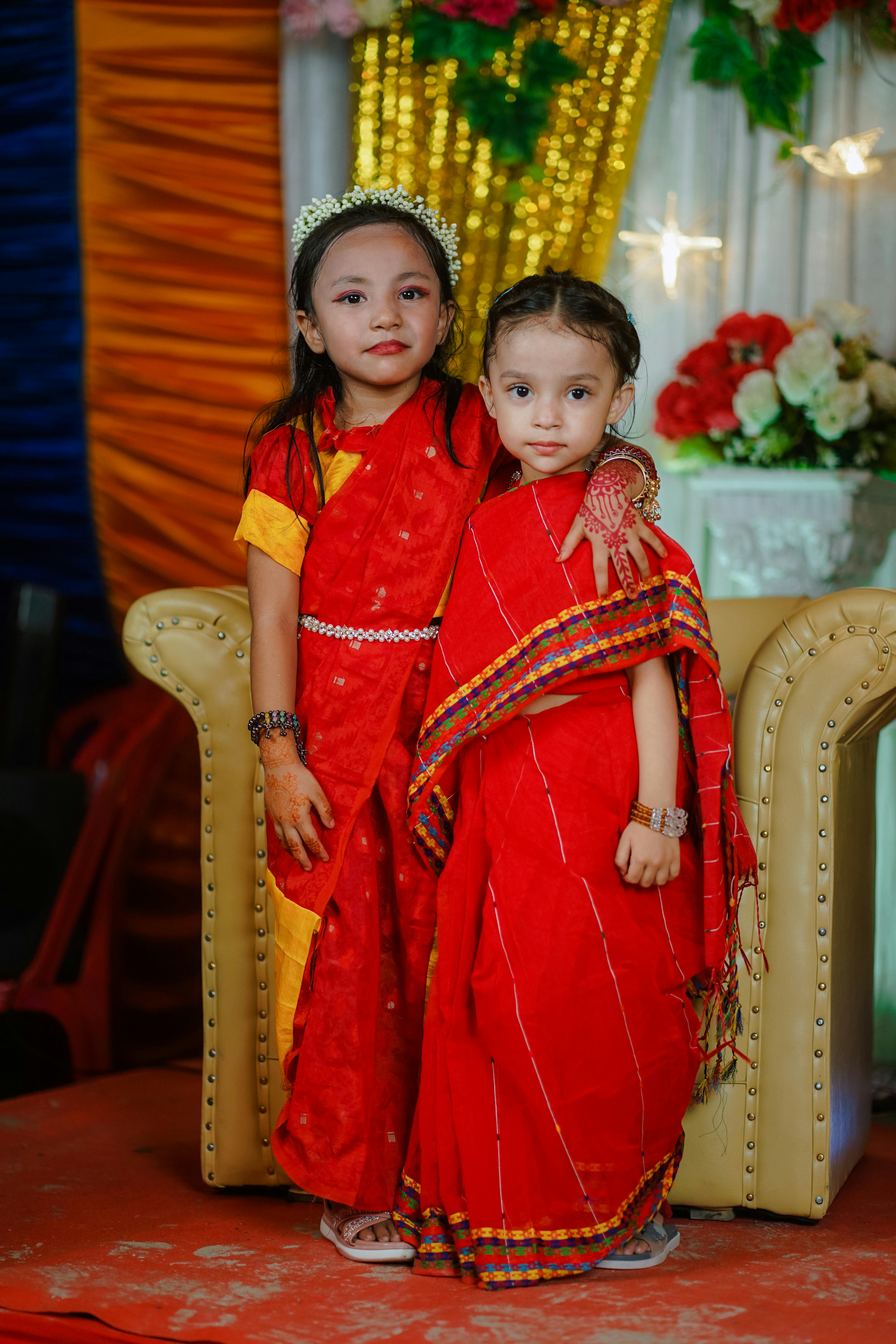 Two smiling Bengali girls in vibrant traditional dress at a festive event.