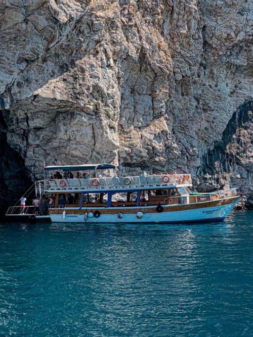 Free A wooden boat docked by a rocky coastline in Muğla, Türkiye's Aegean region. Stock Photo