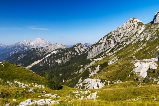 Breathtaking landscape of the Julian Alps featuring rocky peaks and a bright azure sky.
