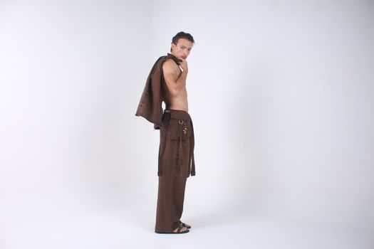 Fashion model striking a pose in elegant brown clothing against a white backdrop.