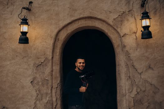 Photographer standing in an archway of traditional Dubai architecture with vintage lighting.