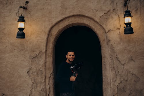 Free Photographer standing in an archway of traditional Dubai architecture with vintage lighting. Stock Photo