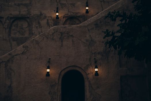 Capture of traditional vintage architecture lit by warm lanterns in Old Dubai at twilight.