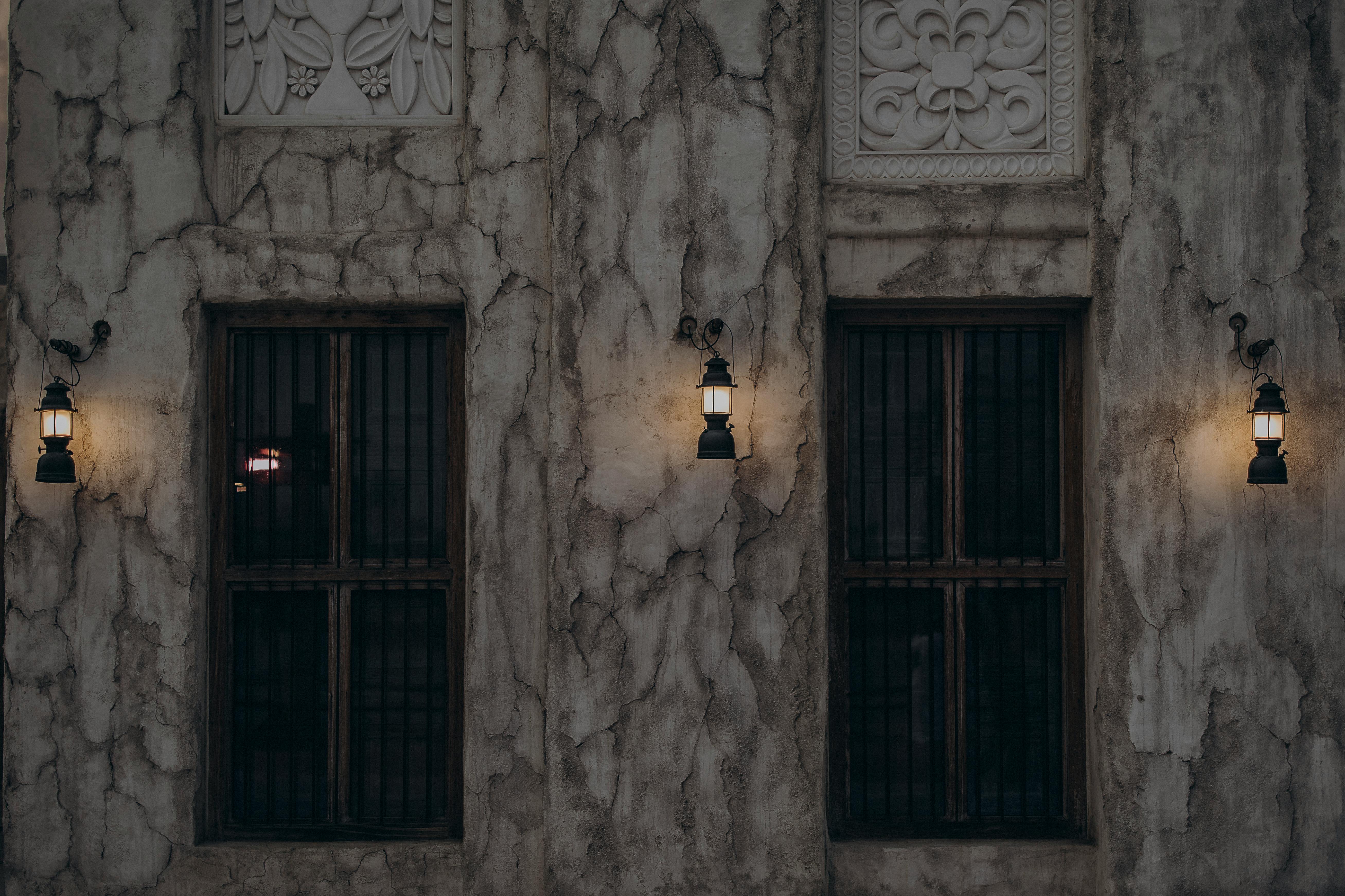 Free Vintage Dubai architecture featuring rustic windows and warm lantern lighting on a textured wall. Stock Photo