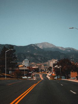 A city road leading to mountains in Colorado Springs under a clear sky.