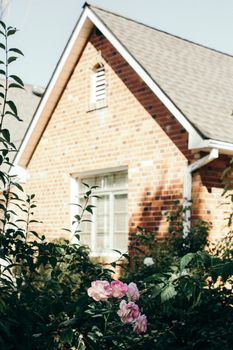 Beautiful brick cottage surrounded by lush rose garden bathed in natural sunlight, capturing serenity.