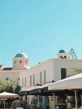 Discover the tranquil beauty of Kos, Greece, featuring iconic blue domes and white buildings under a bright summer sky.