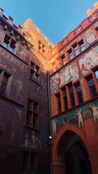 Explore the vibrant murals and Gothic architecture of Basel Town Hall courtyard.