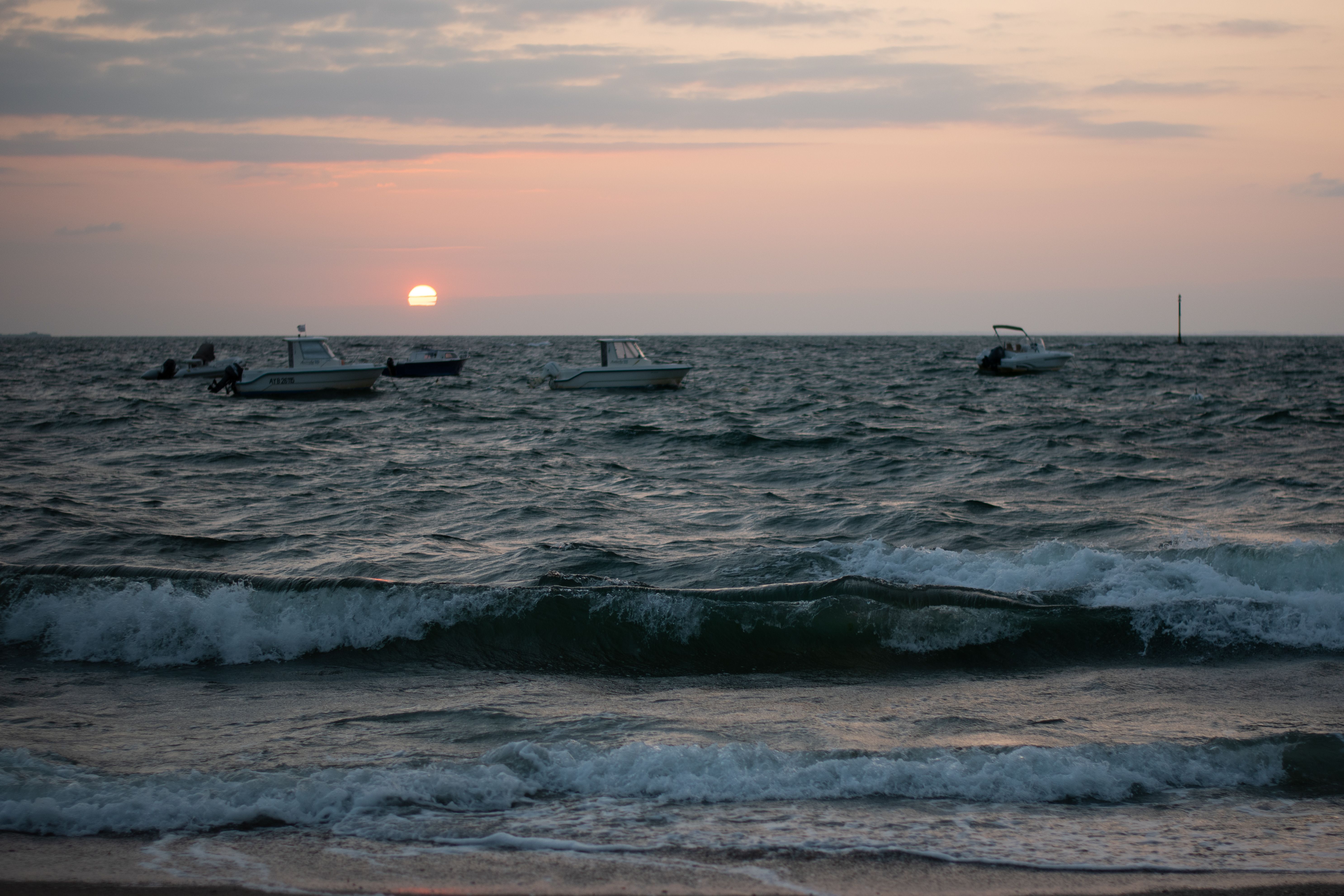 Serene Sunset Over Ocean with Boats on Horizon · Free Stock Photo