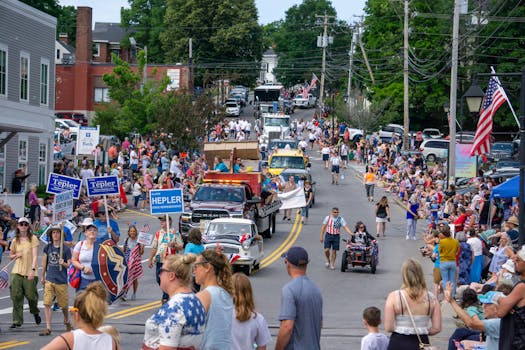 Crowds gather on a sunny day for a festive parade with colorful floats and banners.