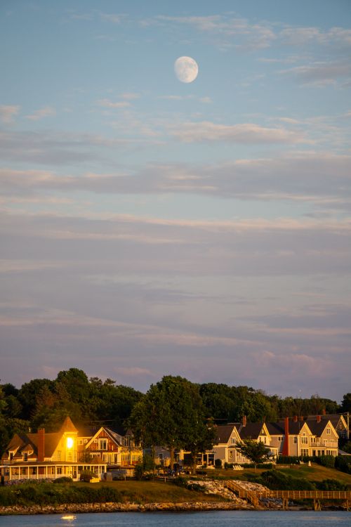 Free Picturesque suburban location with charming houses under a vibrant twilight sky and full moon. Stock Photo