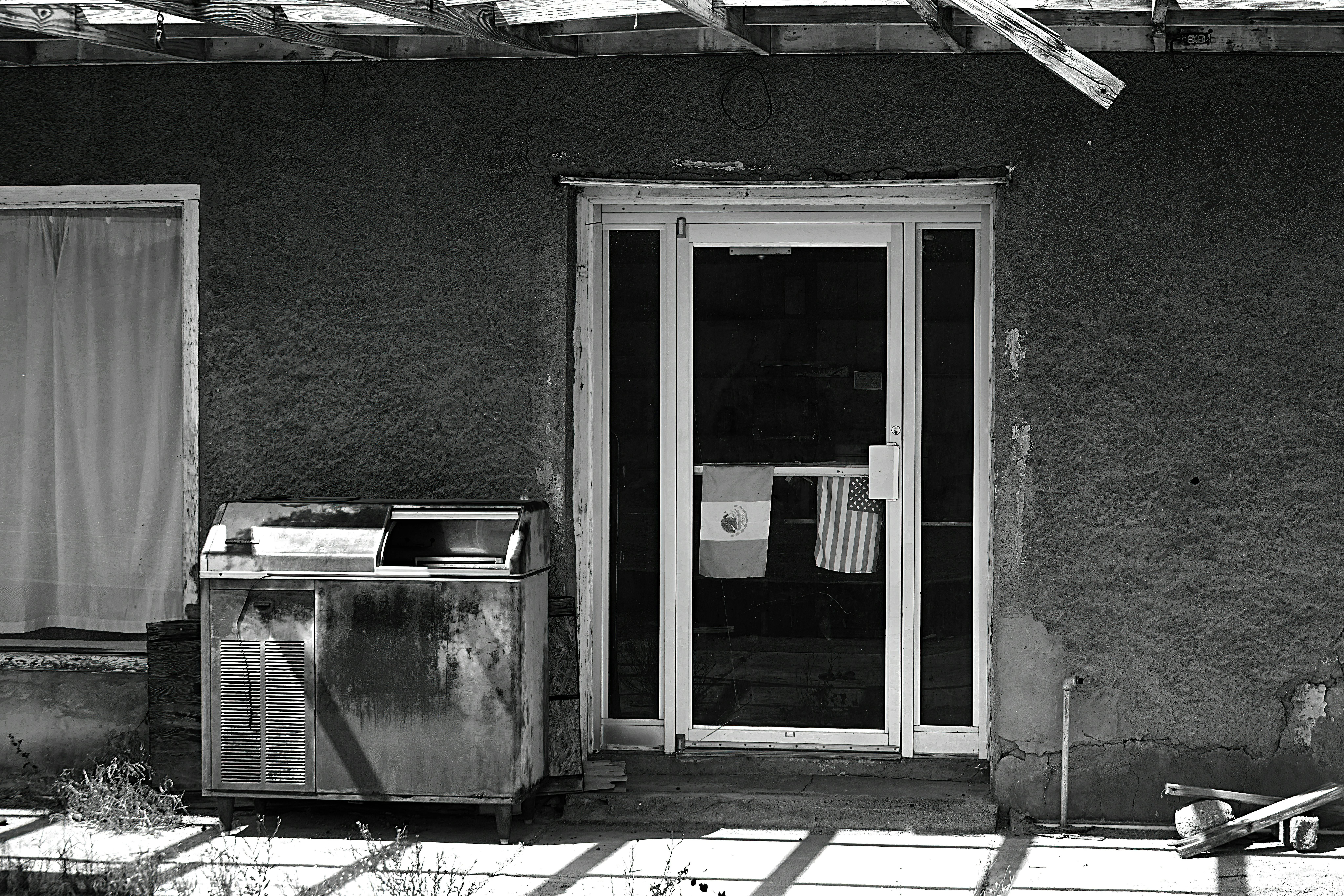 Black and white photo of a weathered, old building with flags, creating a vintage feel.