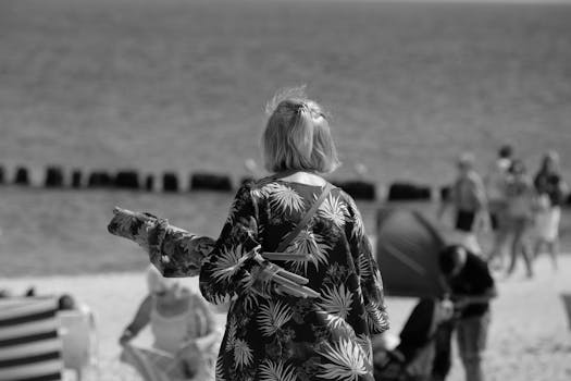 Monochrome photo captures a calm beach scene with people enjoying a day outdoors.