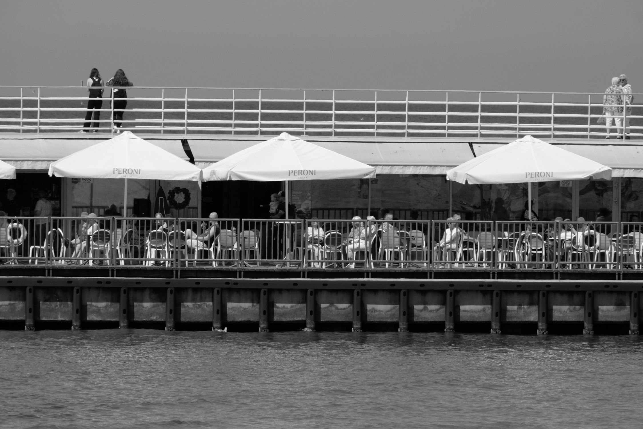 Black and White Pier Cafe Scene with Umbrellas · Free Stock Photo