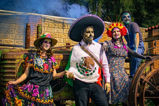 Four people in Catrina costumes showcasing Mexican culture in a colorful outdoor setting.