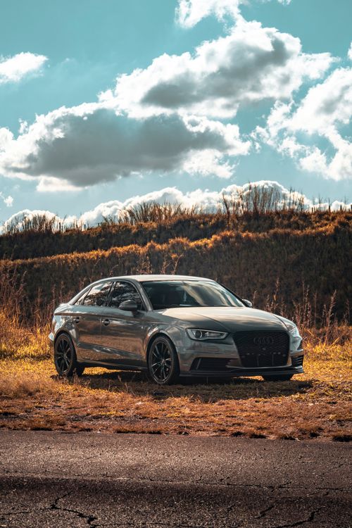 Free A modern silver car parked in a sunny outdoor landscape with clear blue skies. Stock Photo