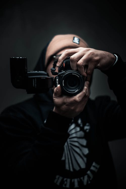 Man in Black Hoodie Using a Black Camera