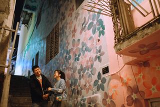 Couple in a mural-covered alley at night — photo by Huy Nguyễn on Pexels