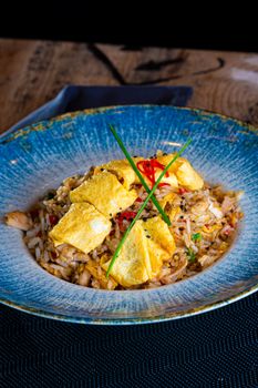 A vibrant dish of chicken fried rice topped with a sliced omelette, garnished with herbs.