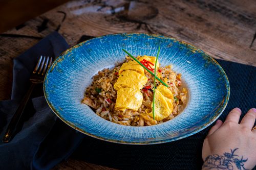 Free Tasty fried rice topped with an omelette, served in a rustic setting. Stock Photo