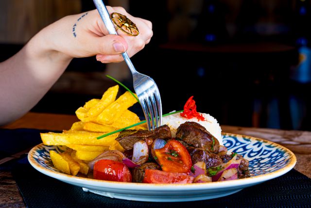 A vibrant plate of Lomo Saltado with fries being enjoyed indoors.