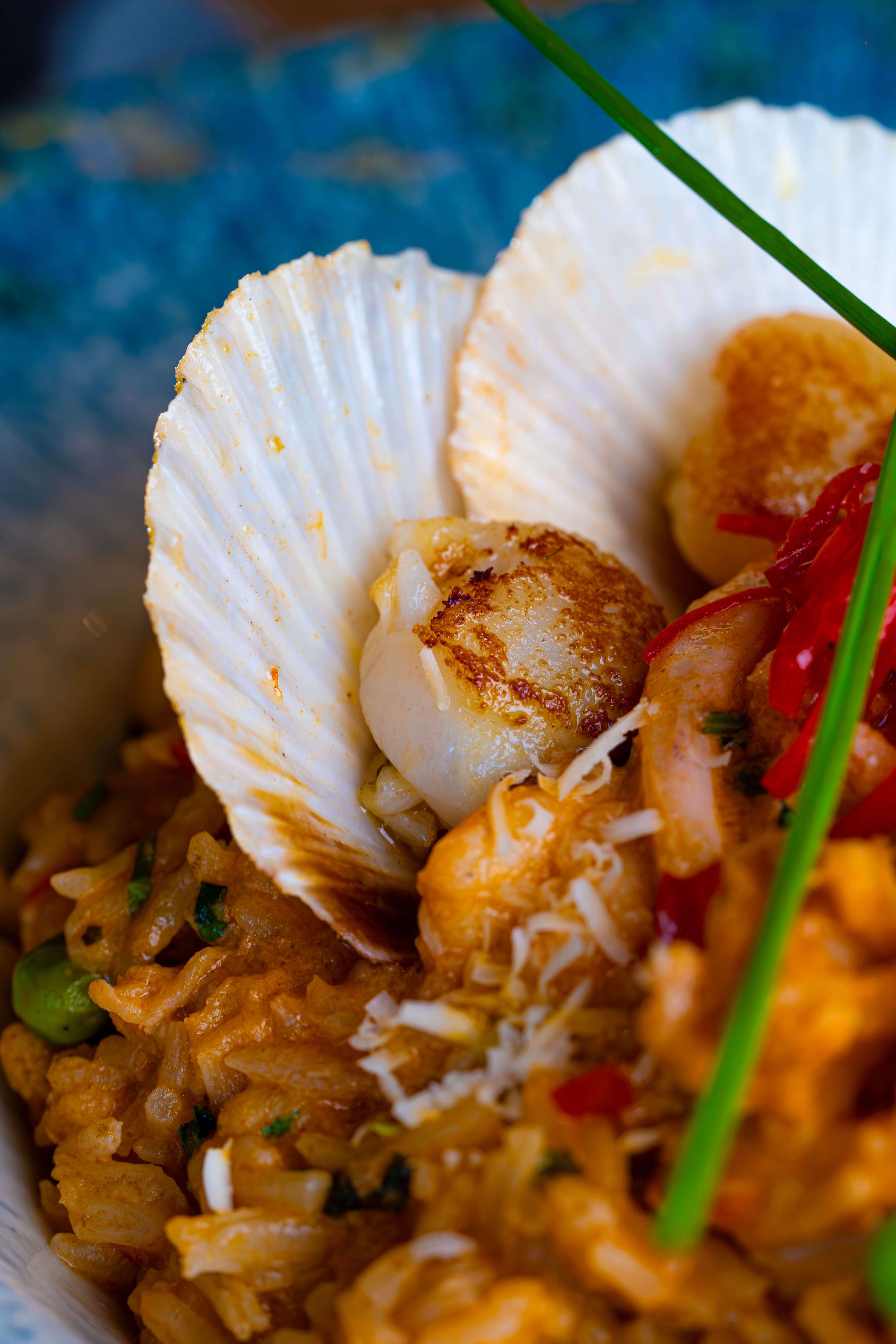Delicious seared scallops served atop creamy risotto with chives and vegetables.