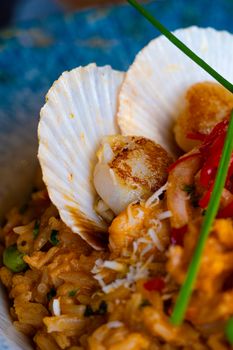 Delicious seared scallops served atop creamy risotto with chives and vegetables.