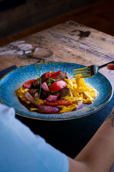 Colorful gourmet pasta with vegetables served on a rustic table setting.