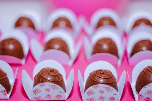 Free Rows of enticing chocolate truffles elegantly placed in floral wrappers for a celebration. Stock Photo