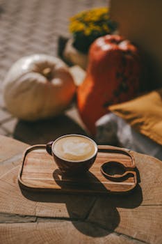Warm and inviting autumn scene with a latte and pumpkins on a rustic table.