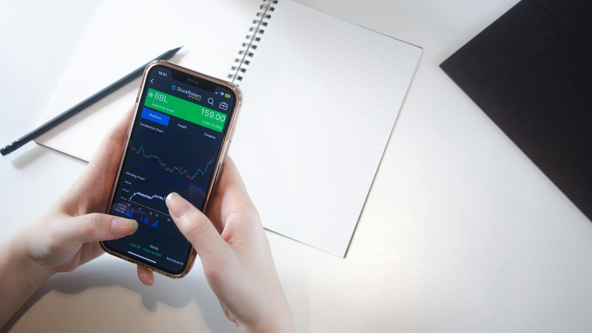 Investor Tracking Real-Time Stock Data on Phone with Notebook