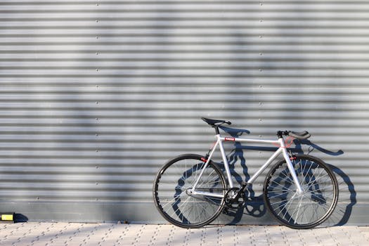A sleek modern bicycle stands against a corrugated metal wall, casting shadows.