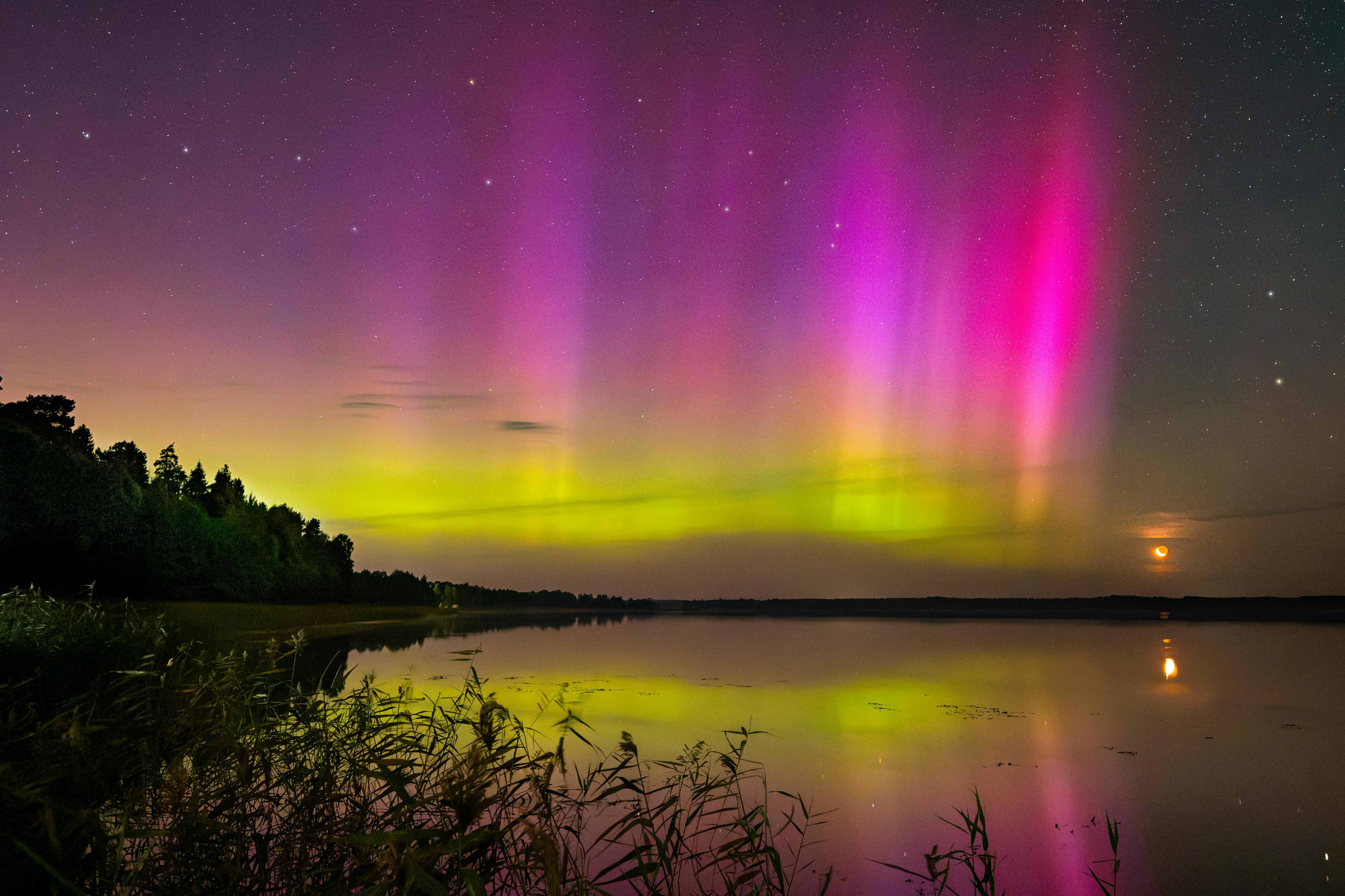 Vibrant Northern Lights illuminate night sky over serene lake reflecting colorful auroras.