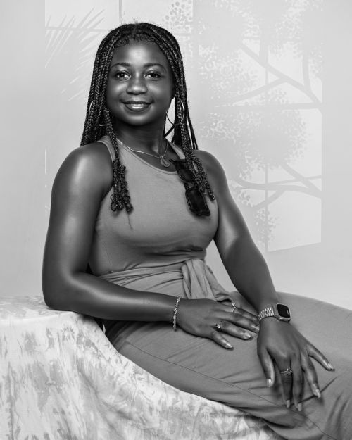 Free Striking black and white portrait of a woman in a relaxed pose with braided hair and a neutral background. Stock Photo