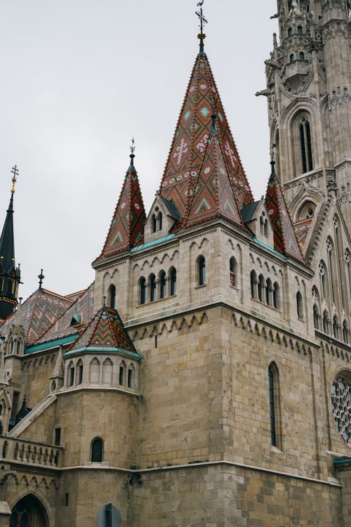 Free Explore the intricate Gothic architecture of Matthias Church in Budapest, featuring decorative spires and colorful roof tiles. Stock Photo