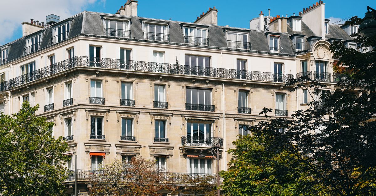 Elegant French architecture with trees under a bright sky, showcasing Parisian charm.