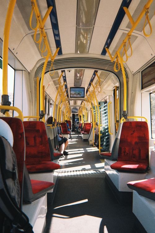 Free Empty Warsaw tram interior with yellow handrails and red seats in daylight. Stock Photo