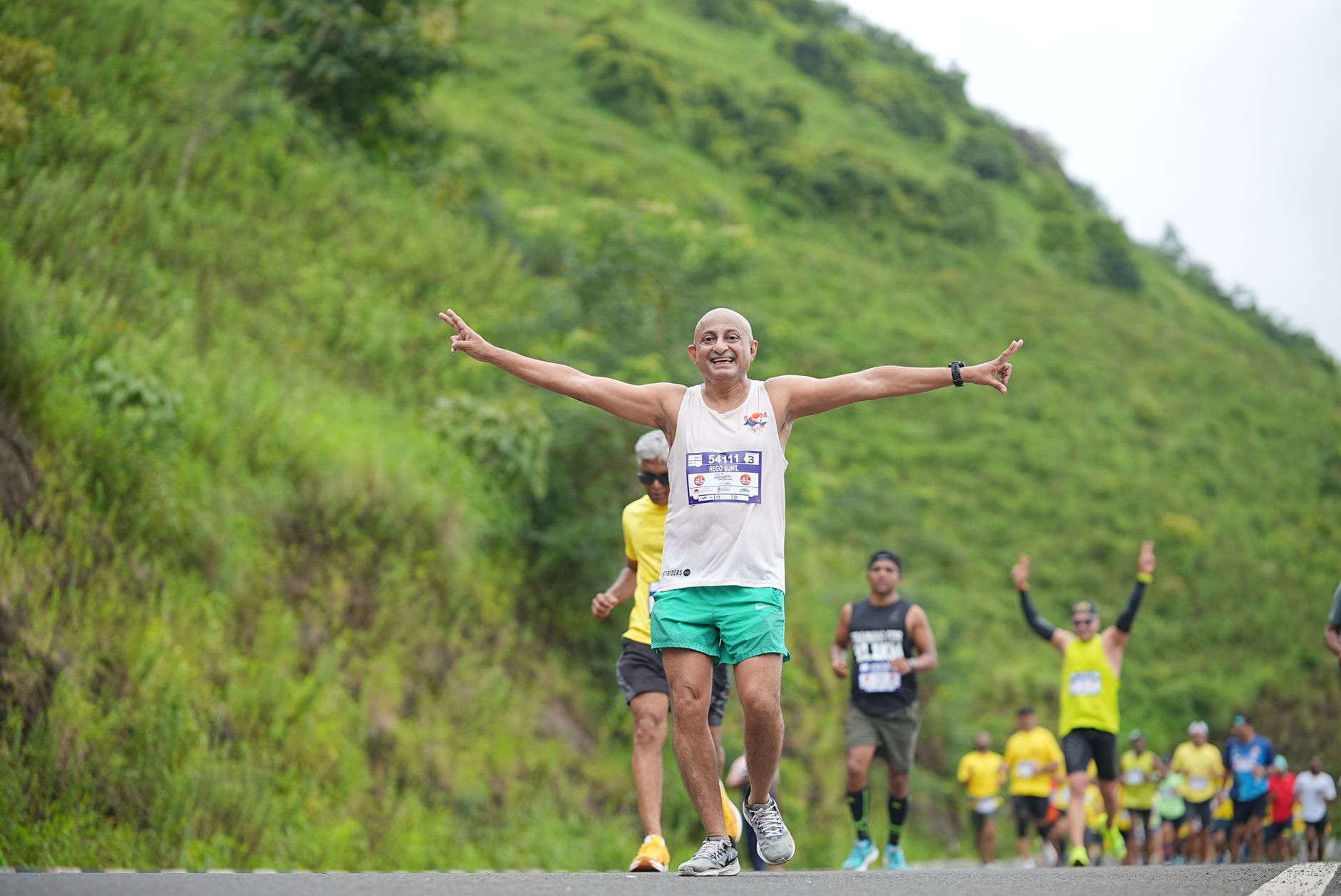 Group of diverse runners enthusiastically participating in a marathon on a lush green path.