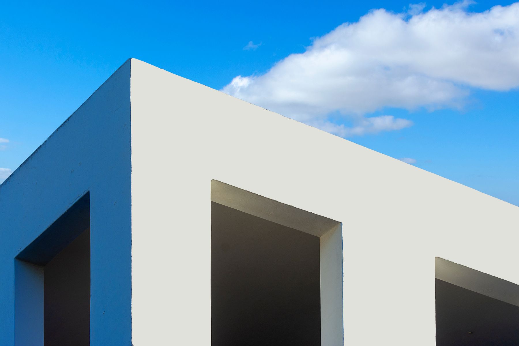 Minimalist white building volume under a clear sky