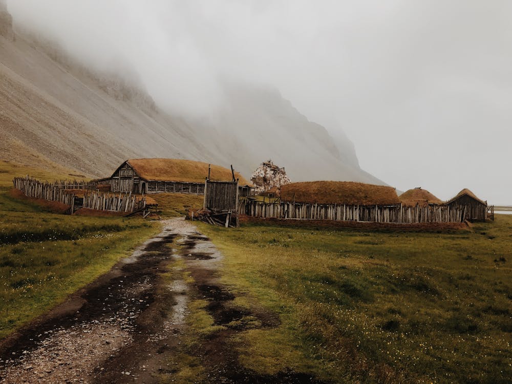 Cottage Houses Below A Foggy Mountain