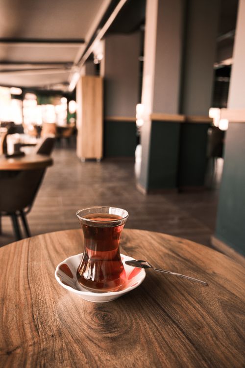 Free A glass of tea sits gracefully on a wooden table inside a cozy cafe. Stock Photo