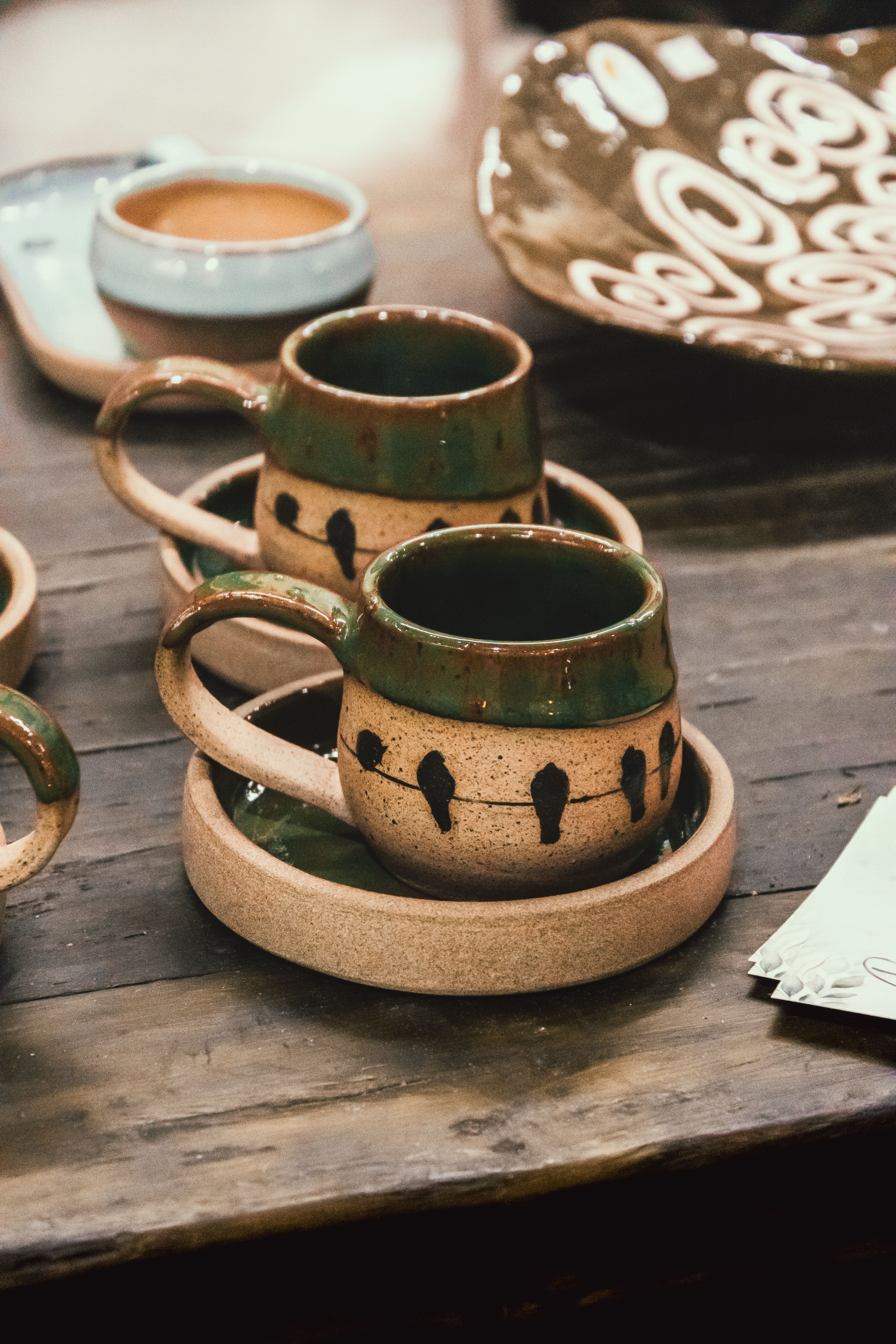 handmade ceramic mugs in warm earthy colors on a pottery table