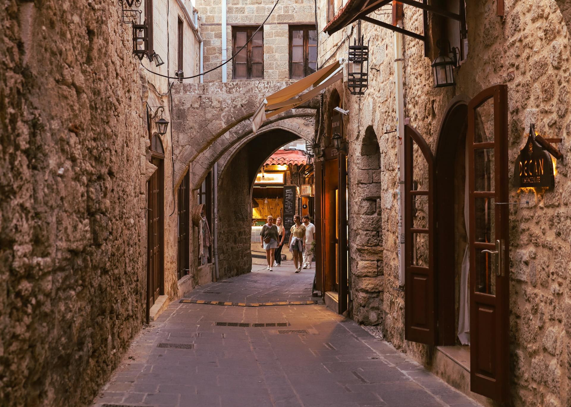 Charming cobblestone street in Old Town Rhodes with classic stone architecture and warm lighting.
