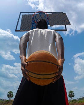 Back view of a basketball player holding a ball under a clear sky in Nigeria.