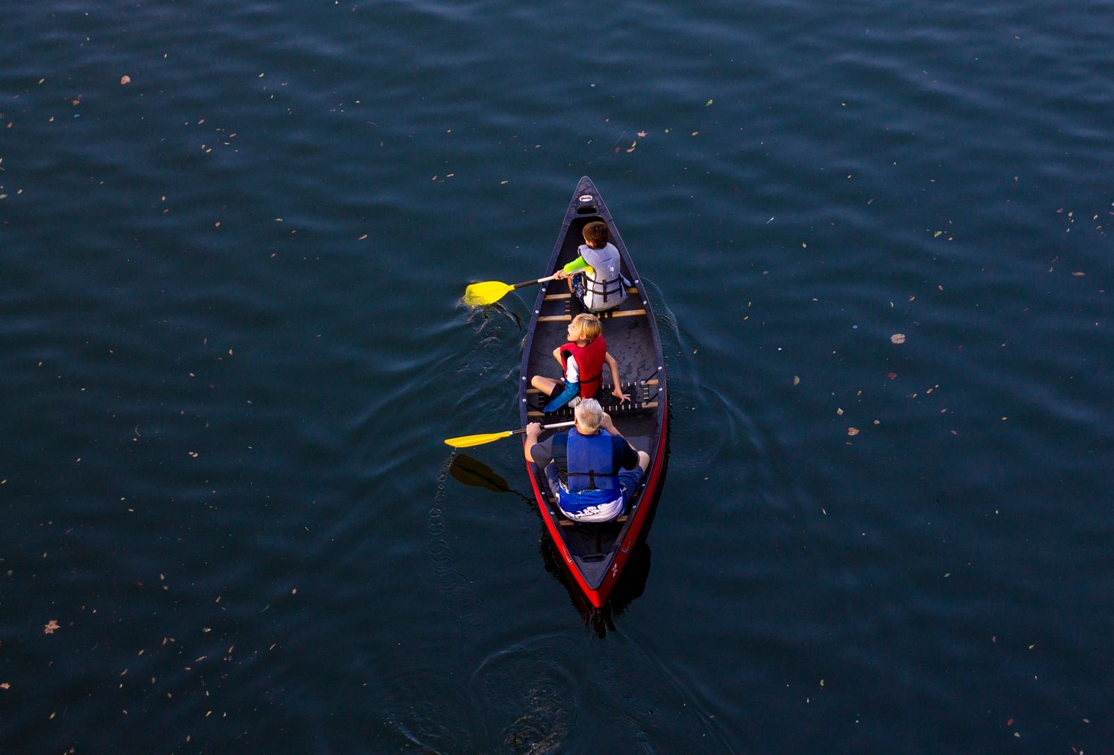 A family paddling a red canoe on the lake