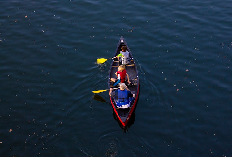 People Riding Red Canoe Boat