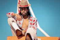 一位时尚男子头戴帽子，身穿充满活力的服装，在纽约布鲁克林的户外摆着姿势