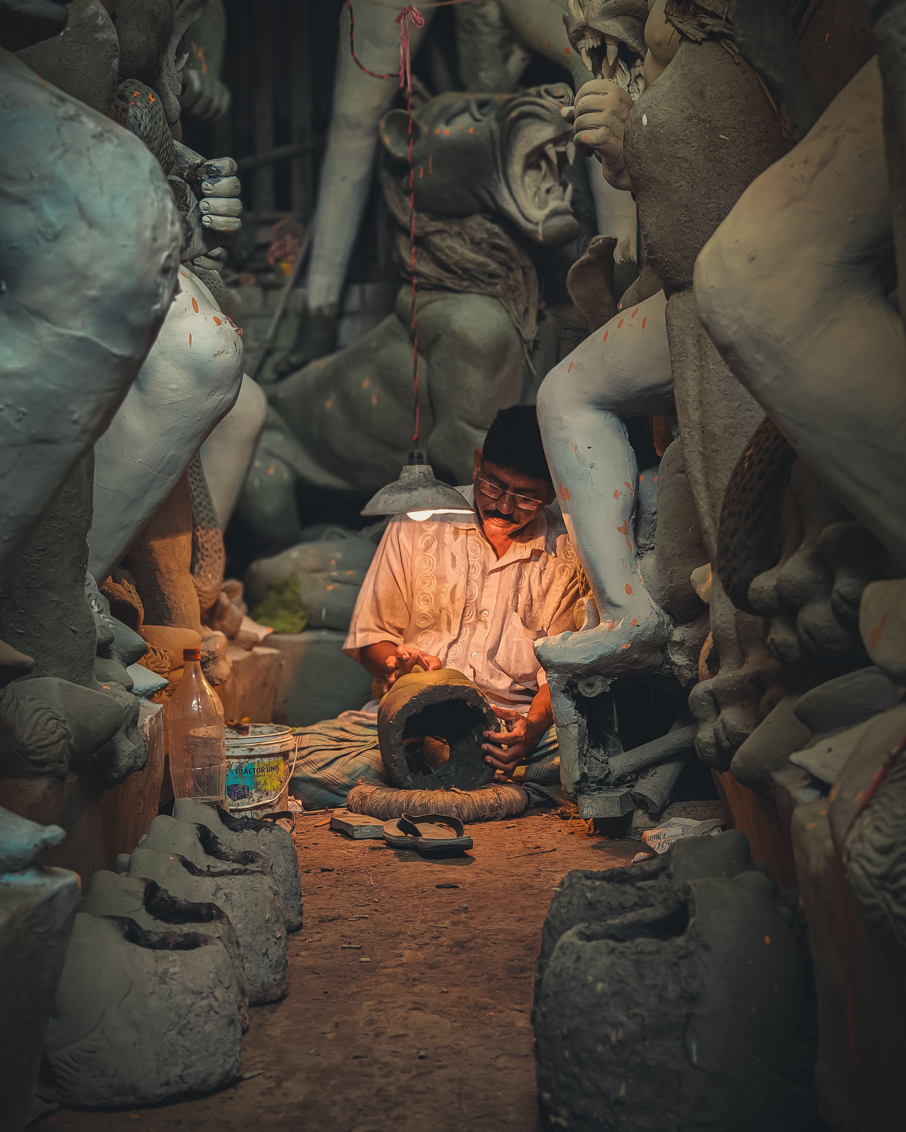 Intricate clay sculpture crafting in a dimly lit workshop in Kolkata. A skilled artisan shapes traditional art.