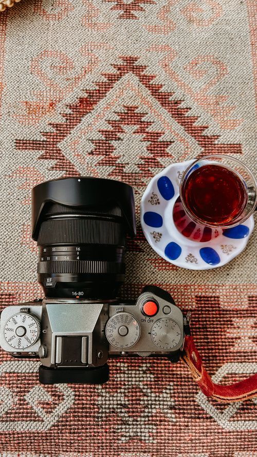 Free Camera and tea on a decorative rug creating a cozy vibe. Stock Photo